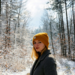 a woman in a yellow hat is standing in the snow