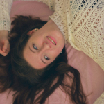 a woman laying on a bed with a pink blanket