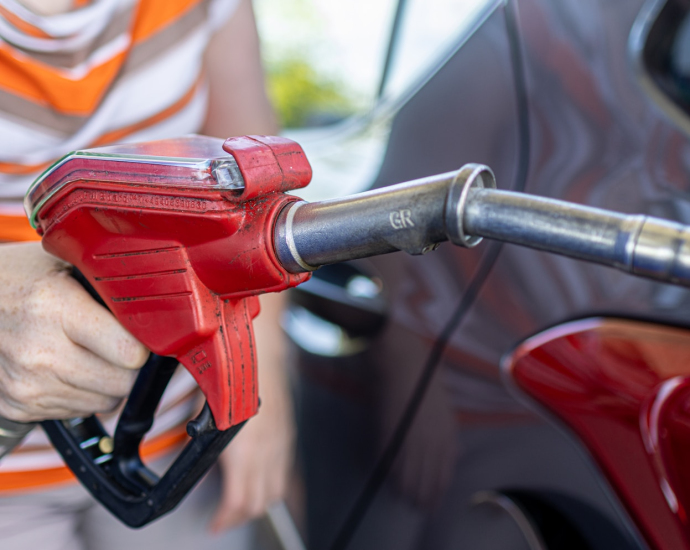 a woman filling a car with gas at a gas station