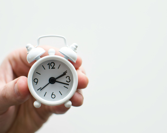 person holding white mini bell alarmclock