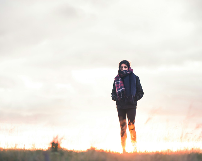 woman walking on green grass under cloudy sky at daytime