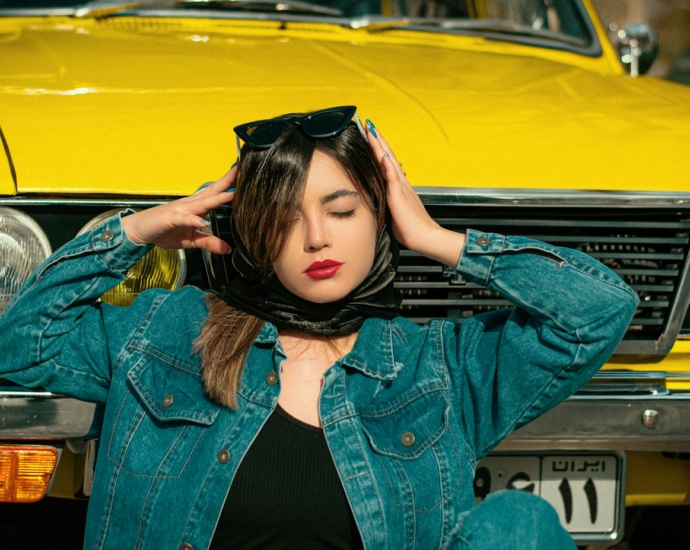 a woman with her head in her hands standing next to a yellow car