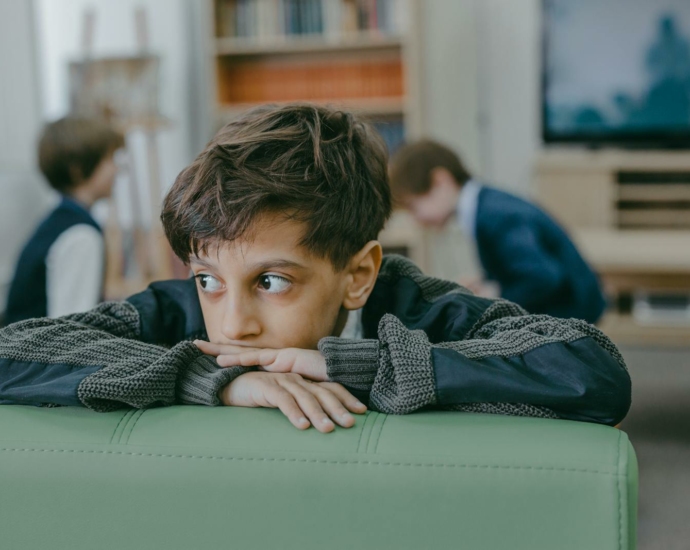 Boy in Black and White Long Sleeve Shirt Sitting on Green Leather Couch