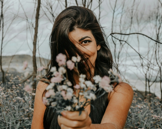 woman holding white flowers surrounded by bare trees