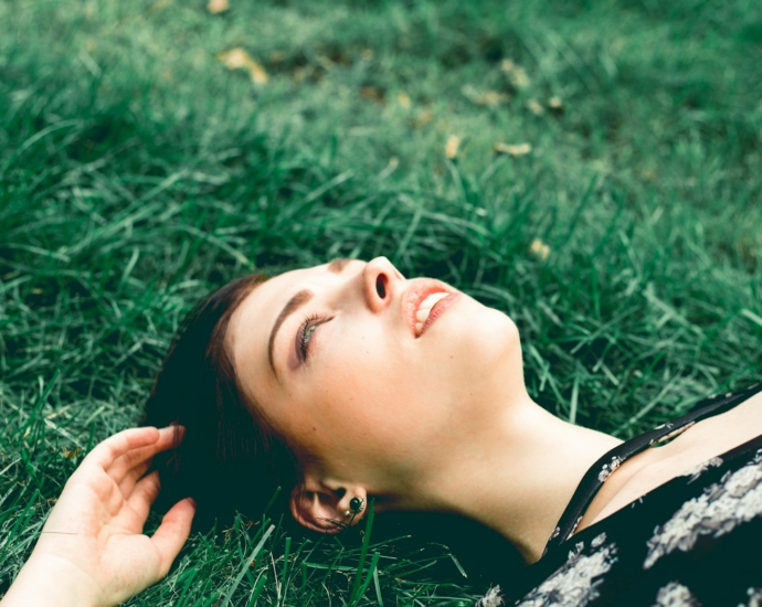 woman in black and white floral shirt lying on green grass field