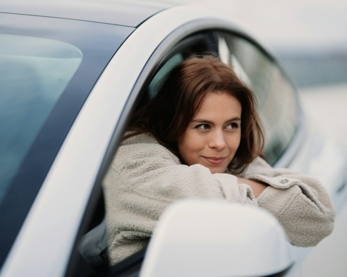 woman in gray coat leaning on white car