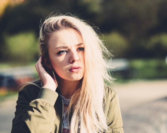 woman touching her hair near trees