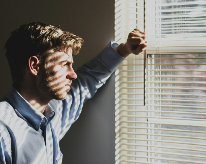 person near clear glass window pane and window blinds low-light photography