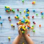 selective photo of kid holding candies on gray wooden pallet board