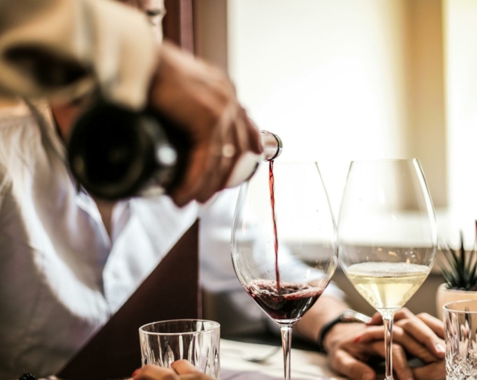 Crop man pouring red wine in glass in restaurant