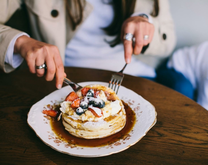 Person Eating Pancakes with Fresh Fruits