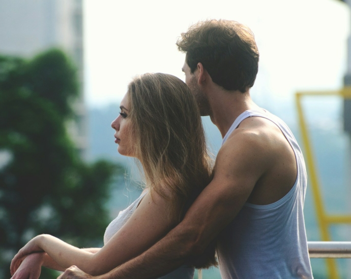 man hogging woman leaning on rail