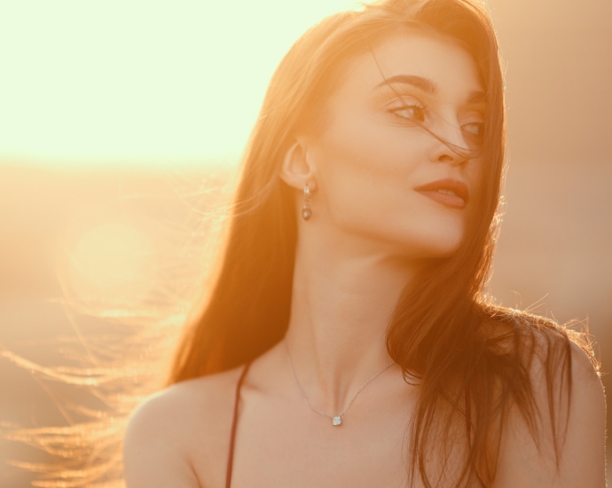 a woman with long hair wearing a necklace and earrings