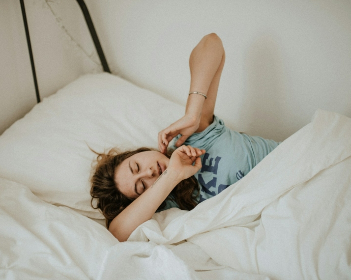 woman covered in white blanket sleeping on white bed comforter