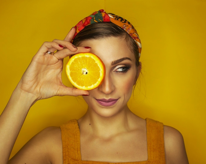 woman covering her right eye with orange slice