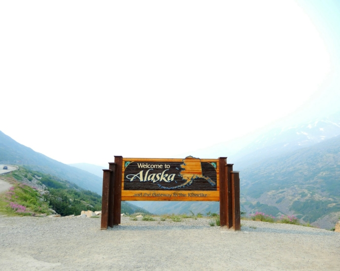 brown wooden signage on gray sand during daytime