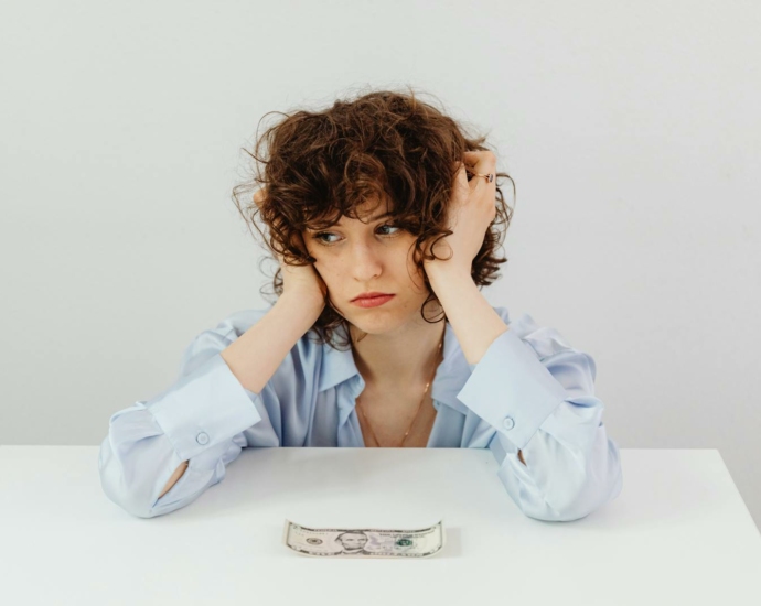 Woman in Blue Long Sleeve Blouse Near the Money on Table