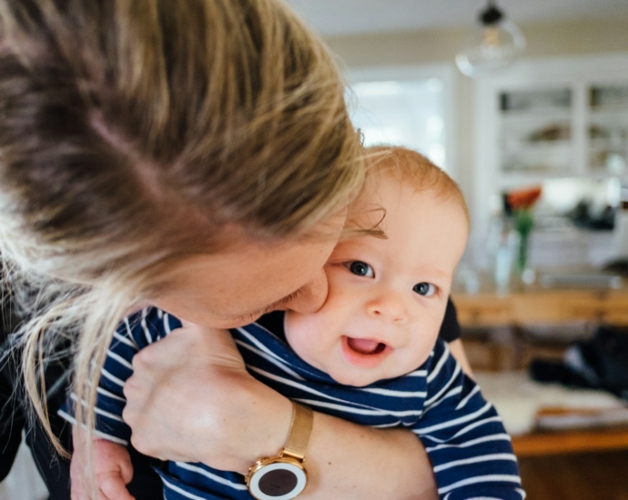 woman carrying baby in striped shirt