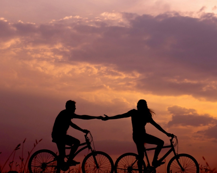 woman on bike reaching for man's hand behind her also on bike