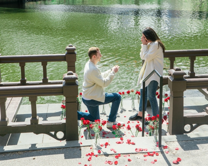 woman in white shirt sitting on brown wooden bench near body of water during daytime