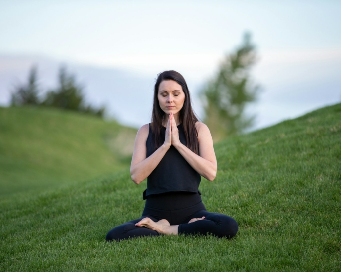 woman in black tank top and black pants sitting on green grass field during daytime