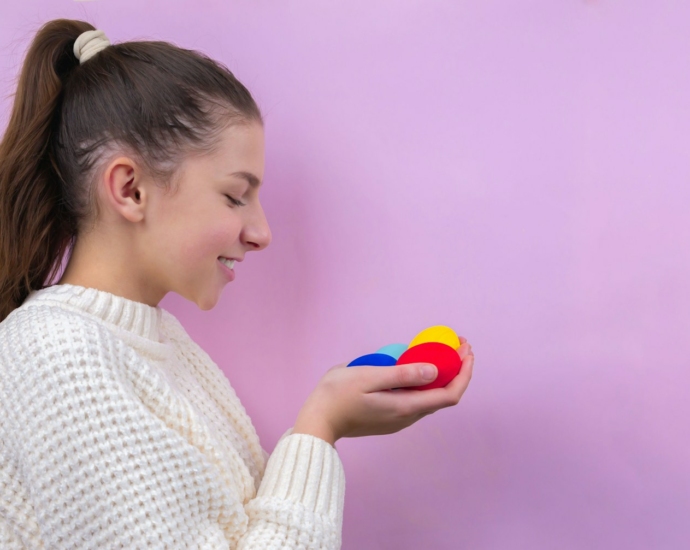 woman in white knit sweater holding blue ball