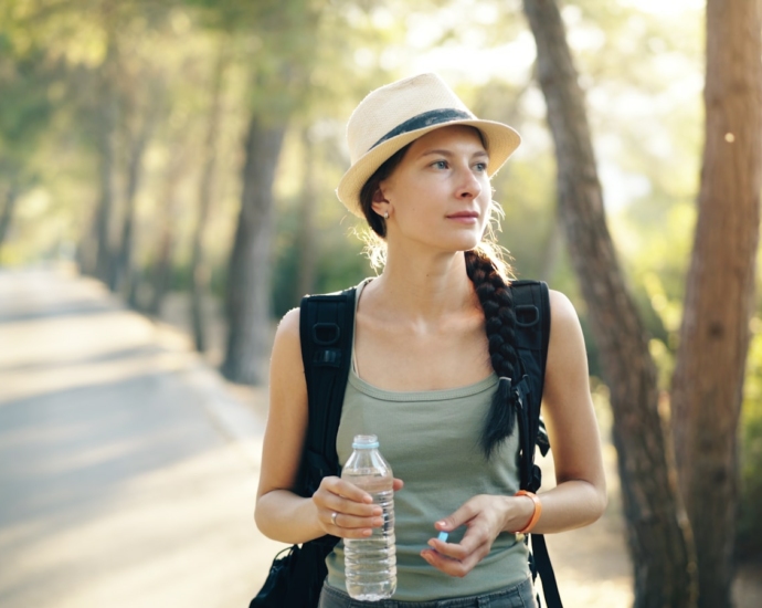 a woman in a hat is holding a water bottle