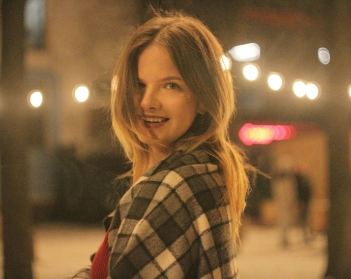 a woman standing on a sidewalk with a plaid coat on