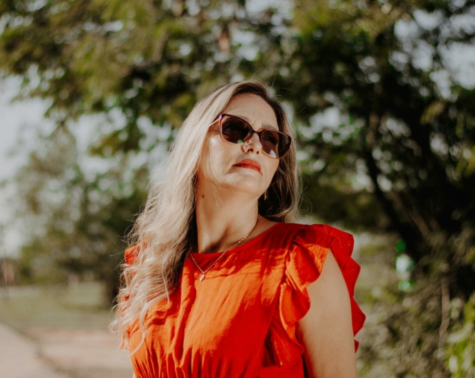 A woman in sunglasses and red dress standing on a path