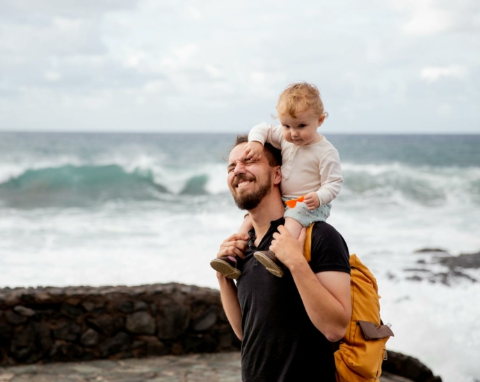 Man in Black Shirt Carrying Little Kid on His Shoulder