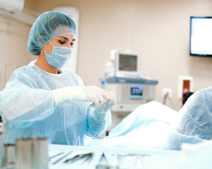 Woman in Blue Dress Shirt Wearing Blue Mask and White Latex Gloves