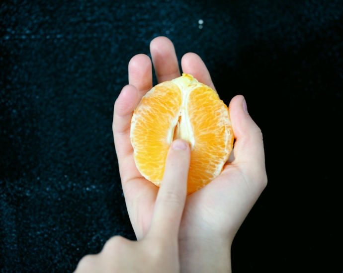 person holding sliced orange fruit