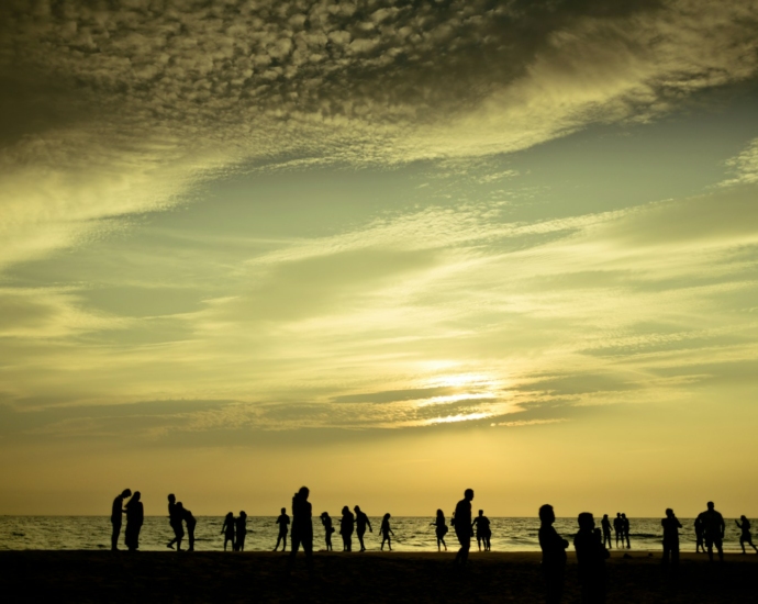 silhouette of people standing on beach during sunset