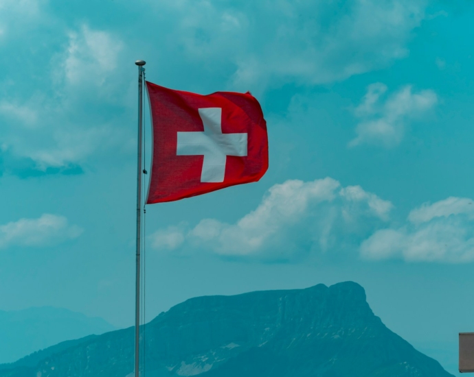 red and white cross flag on pole under blue sky during daytime