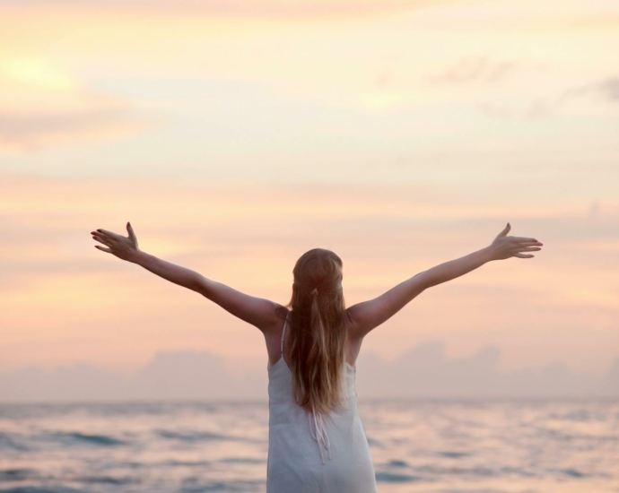 Rear View of Woman With Arms Raised at Beach during Sunset