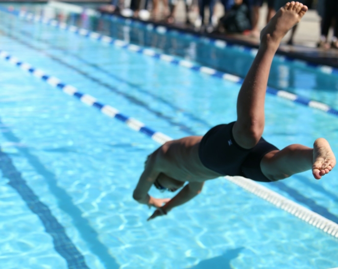 woman in black one piece swimsuit jumping on swimming pool during daytime