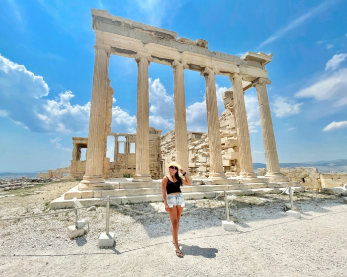 woman in black tank top and blue denim shorts standing near brown concrete building during daytime