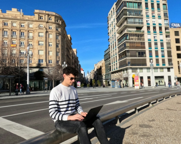 a man sitting on a bench using a laptop computer