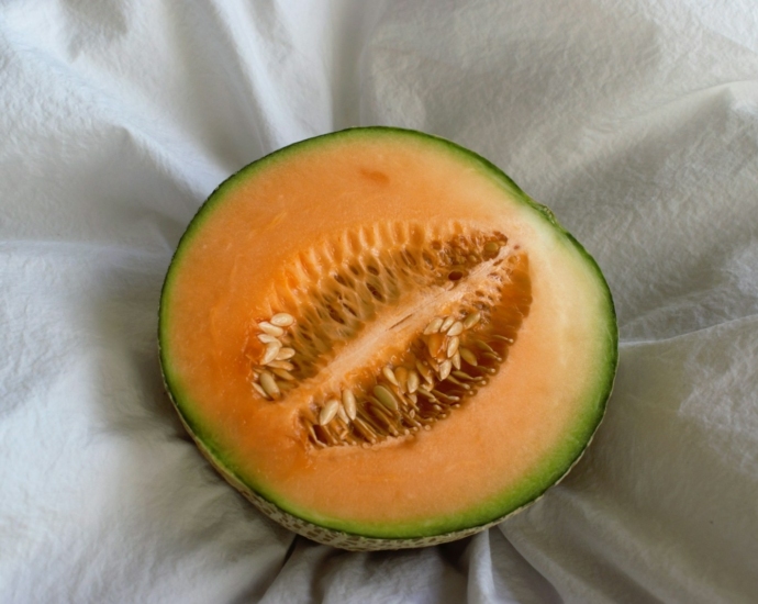 a cut in half melon sitting on top of a white cloth