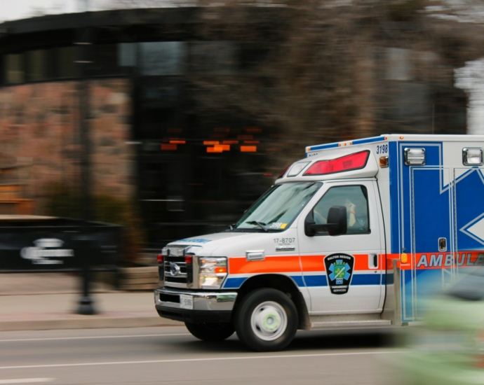 white and blue ambulance van traveling on road