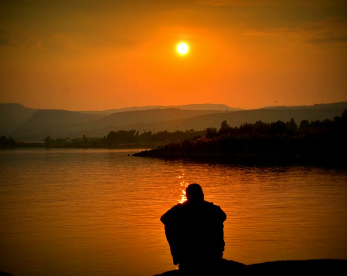 Silhouette of Person Sitting Beside Body of Water