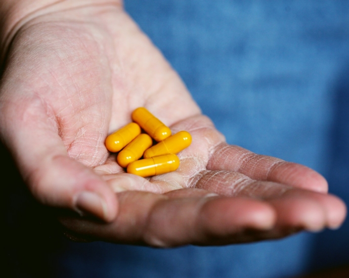 yellow medication pill on persons hand