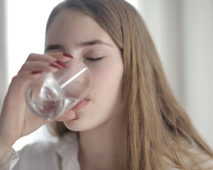 Woman in White Shirt Drinking Water From Clear Glass with Her Eyes Closed