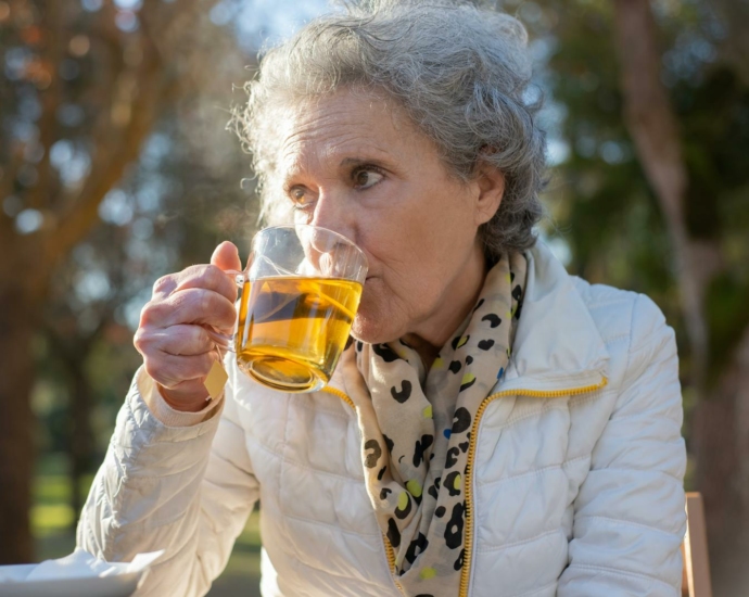 An Elderly Woman in White Jacket Drinking Tea