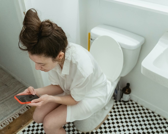 Woman with Cellphone on Toilet Seat