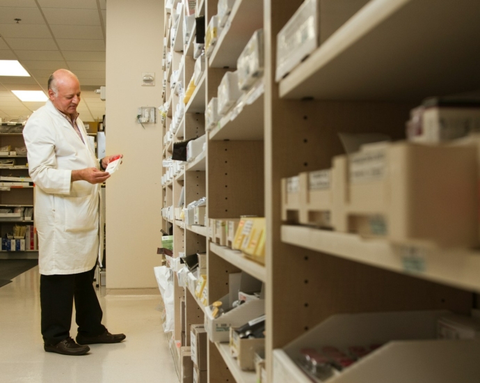 woman in white dress shirt and black pants standing near brown wooden shelf