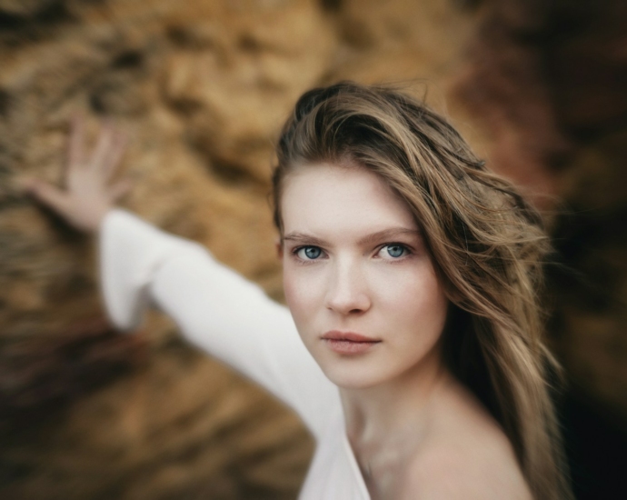 A woman is posing for a picture in front of a rock