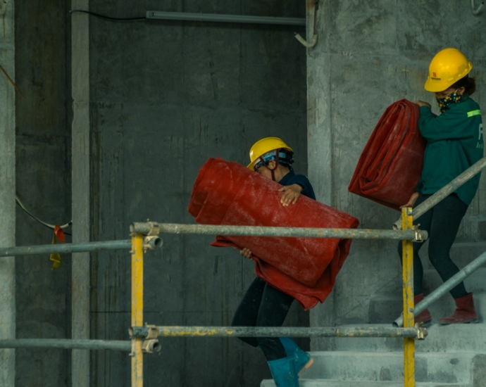 man in orange hard hat holding red plastic bag