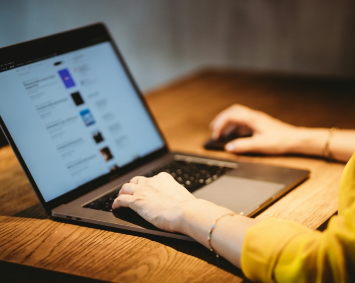 person using macbook pro on brown wooden table