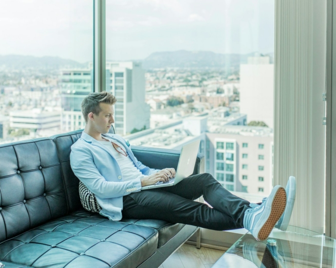 man sitting on sofa while using laptop